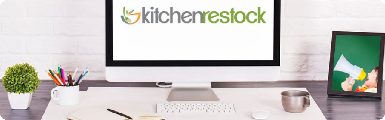 KitchenRestock About Us banner displayed on a desktop monitor in a clean workspace